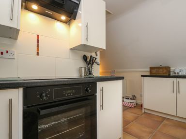 A kitchen with a black oven and white cabinets and tiled floor at Valley Lodge 48 in Callington