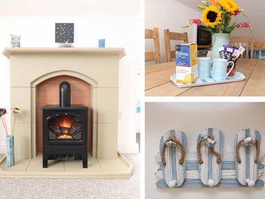 A fireplace with a black stove and a clock above it a wooden dining table with mugs and a vase of sunflowers and a wall hook shaped like flip flops at The Watch in Porthcurno
