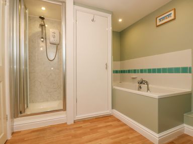 A bathroom with a shower enclosure bathtub and a door at The Watch in Porthcurno