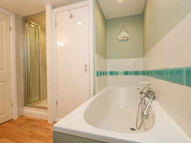 A bathroom with a bathtub next to a shower and a white door at The Watch in Porthcurno