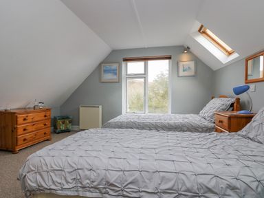 A bedroom with two twin beds wooden furniture and sloped ceiling at The Watch in Porthcurno