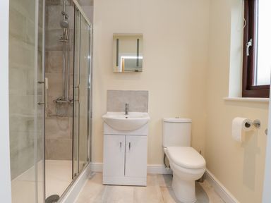 A bathroom with a shower enclosure sink with cabinet toilet and window at Rose Lodge in Sheriff Hutton