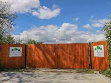 A large closed wooden gate with signs reading Cottage Farm Lodges on either side at Rose Lodge in Sheriff Hutton