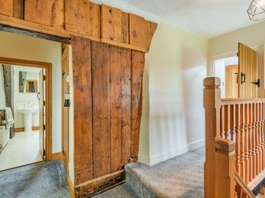 A hallway with wooden paneling and banister next to a bathroom at Gwrtheyrn in Dyffryn Ardudwy