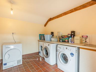 A laundry room with washing machines a dryer and laundry supplies on a countertop at Gwrtheyrn in Dyffryn Ardudwy