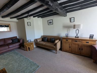 A living room with two sofas wooden side tables a wooden cabinet and a lamp at Gwrtheyrn in Dyffryn Ardudwy