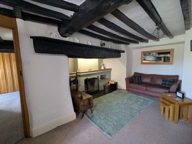 A living room with a brown leather sofa a green rug a wooden side table and a black fireplace at Gwrtheyrn in Dyffryn Ardudwy