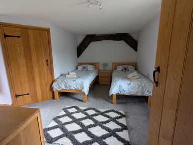 A bedroom with two single beds a bedside table a lamp and a patterned rug at Gwrtheyrn in Dyffryn Ardudwy