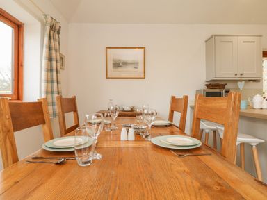 A dining table set with plates glasses and cutlery in a kitchen with wooden chairs at Edwins View in Nancegollan nr Porthleven
