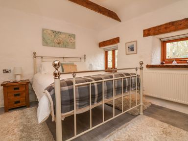 A bedroom with a metal bed frame a wooden bedside table and two windows at Edwin's View in Nancegollan nr Porthleven