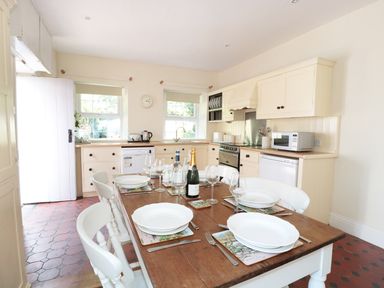A kitchen with a wooden dining table set for six and cream cabinets at School House in Builth Wells