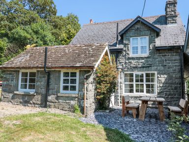 Exterior of a stone house with wooden outdoor furniture on a slate patio at School House in Builth Wells