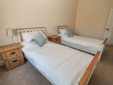 A bedroom with two single beds white bedding wooden headboards bedside tables and silver lamps at Hare & Hounds House in Allendale