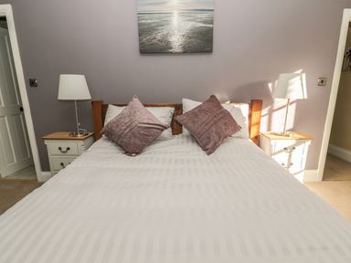A bedroom with a double bed with two pillows two bedside tables with lamps and a picture above the bed at Hare & Hounds House in Allendale