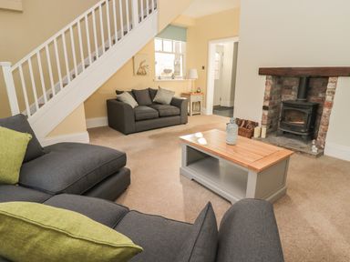 A sitting room with two gray sofas green cushions a wooden coffee table and a fireplace at Hare & Hounds House in Allendale