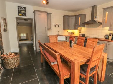 A kitchen with wooden dining table and chairs next to grey cabinets and appliances at Hare  Hounds House in Allendale