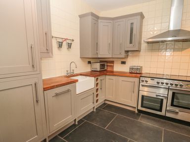 A kitchen with cabinets a farmhouse sink a stove a toaster and a microwave at Hare & Hounds House in Allendale