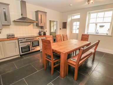 A kitchen with wooden dining table set and stainless steel oven and cabinets at Hare & Hounds House in Allendale