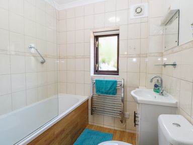 A bathroom with a bath, toilet, sink and towel rail at Lowbrook Cottage in Dickleburgh near Diss