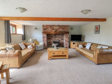 A living room with a fireplace and sofas at Glanyrafon in St Harmon