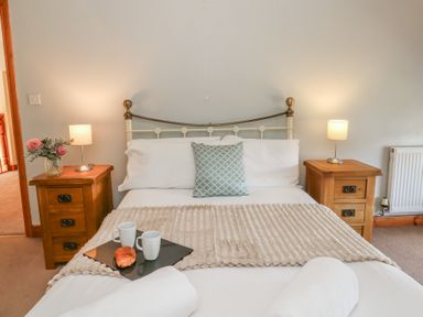 A bedroom featuring a bed with pillows and a bedside table at Glanyrafon in St Harmon