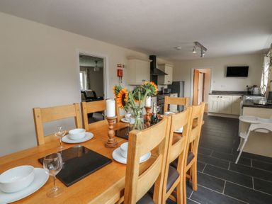 A dining room with a table and chairs at Glanyrafon Bungalow in St Harmon