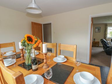 A dining room with a table set for a meal at Glanyrafon Bungalow St Harmon