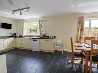 A kitchen with a dining table and chairs at Glanyrafon Bungalow in St Harmon