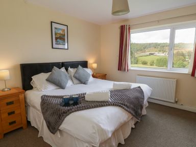 A bedroom with a large bed and countryside view at Glanyrafon Bungalow St Harmon
