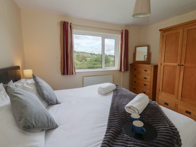 A bedroom with a bed and window at Glanyrafon Bungalow in St Harmon