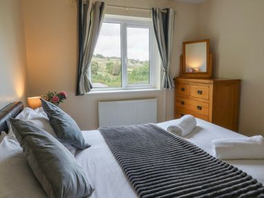 A bedroom with a bed and window view at Glanyrafon Bungalow, St Harmon