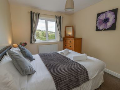 A bedroom with a bed and a dresser at Glanyrafon Bungalow in St Harmon