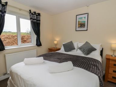 A bedroom with a double bed and nightstands at Glanyrafon Bungalow St Harmon