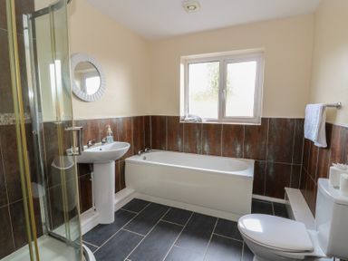 A bathroom with shower, bathtub, sink, and toilet at Glanyrafon Bungalow St Harmon
