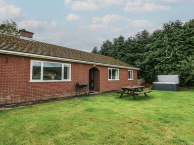 A bungalow with a picnic table and hot tub at Glanyrafon Bungalow in St Harmon