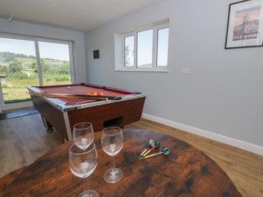 A snug with a pool table and wine glasses at Glanyrafon Bungalow in St Harmon