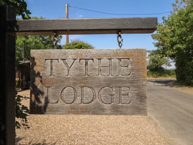 A sign displaying TYTHE LODGE near a gravel road in Howell near Heckington