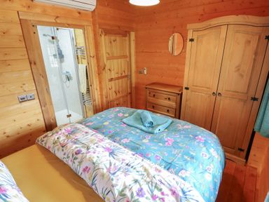 A bedroom with a bed and shower at Tythe Lodge – Hot Tub Retreat in Rural Lincolnshire | Family-Friendly Lodge Near Heckington