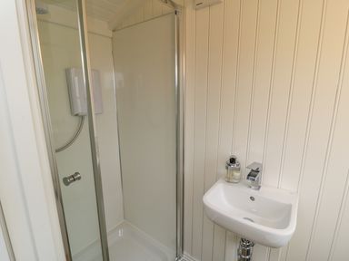 A bathroom with a shower enclosure and a small sink with soap dispenser at Bellwether in Helmsley