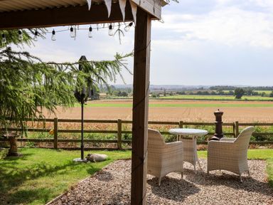 An outdoor patio with two chairs and a small table overlooking fields at Bellwether in Helmsley