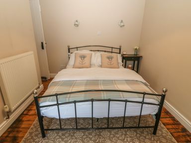 A bedroom with a metal bed frame a side table with flowers and a radiator at Glasfryn in Llanfaethlu