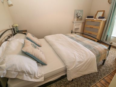 A bedroom with a double bed pillows a dresser and a window at Glasfryn in Llanfaethlu