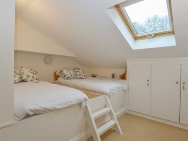 A bedroom with two single beds built into a raised platform under a skylight at Wood View Cottage in Blackawton