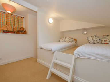 A small bedroom with two single beds on a raised platform and a ladder at Wood View Cottage in Blackawton