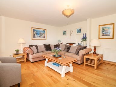 A living room with a beige sofa and wooden coffee table with flowers at Wood View Cottage in Blackawton