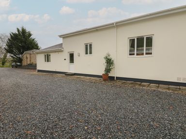The exterior of a single-story building with gravel driveway a potted plant near the door at Wood View Cottage in Blackawton