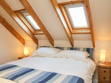 A bedroom with a double bed under skylight windows and bedside tables with lamps at Rose Cottage in Barnstaple