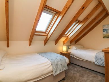 A bedroom with two single beds bedside table and windows in the roof beams at Rose Cottage in Barnstaple