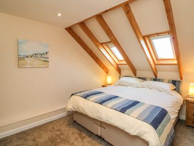 A bedroom with a double bed under two skylight windows and wooden beams at Rose Cottage in Barnstaple