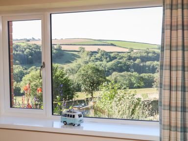 A window with a toy van on the sill and a view of fields and trees at Rose Cottage in Barnstaple